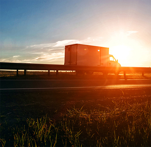 Truck riding on the road at sunset