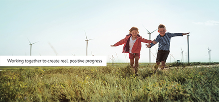 Children playing in grass field with wind turbines in background